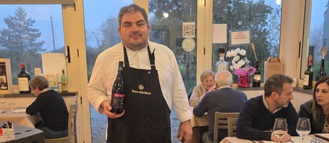 luca usala nella sala della trattoria la loggia con un bicchiere di vinoò in mano è in posa circondato da tavoli apparecchiati dove sono sedute persone in atteggiamento conviviale